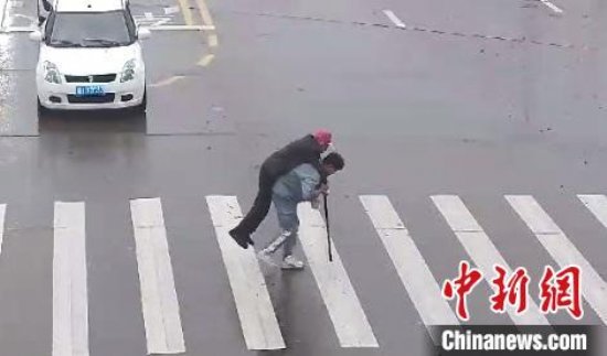 衢州市龙游县街头温暖一幕：小伙下车背拄拐老人过马路